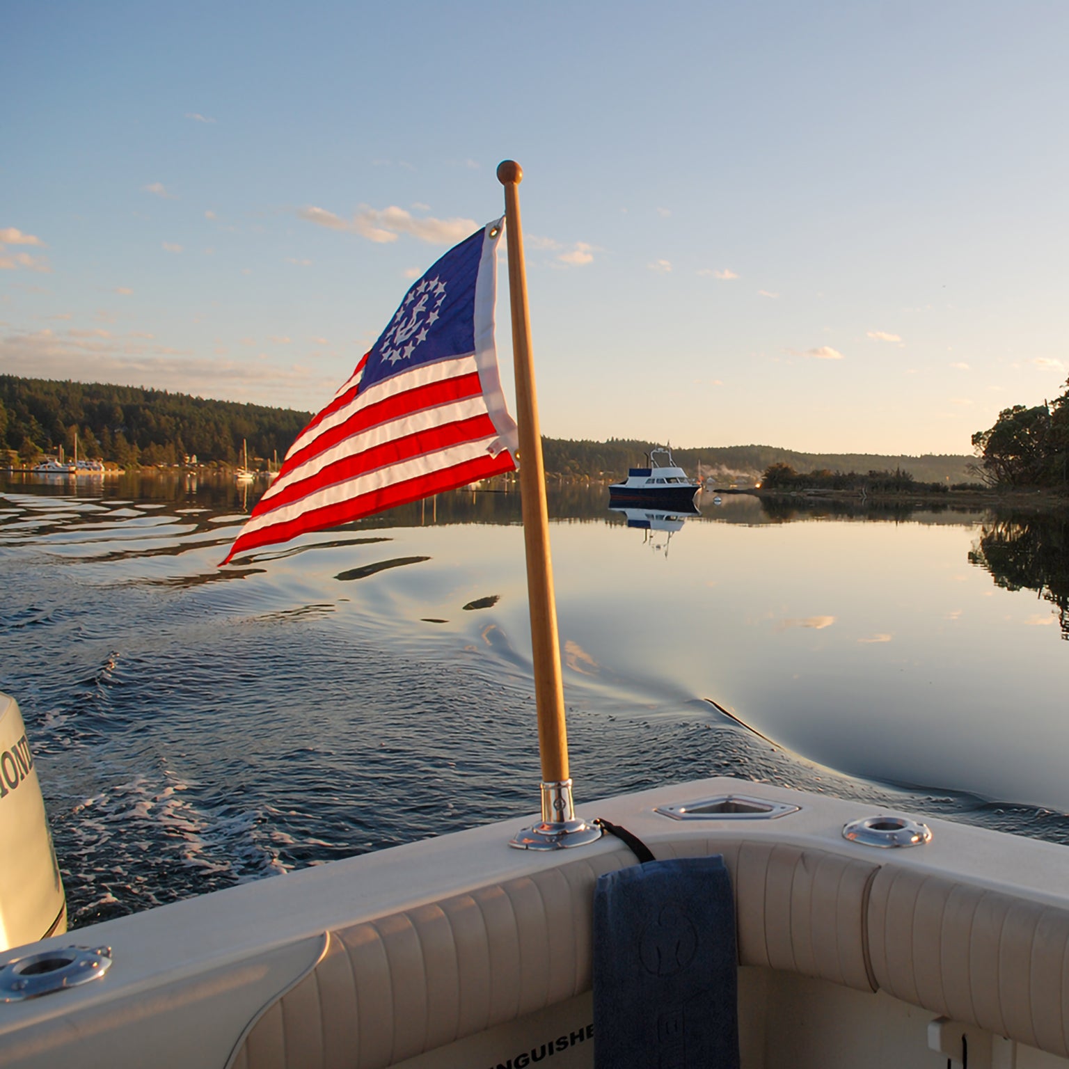 The Burnewiin FL6155 Flag Holder with the American flag flying and inserted into a GM650 that is positioned in the rear port corner of a boat.