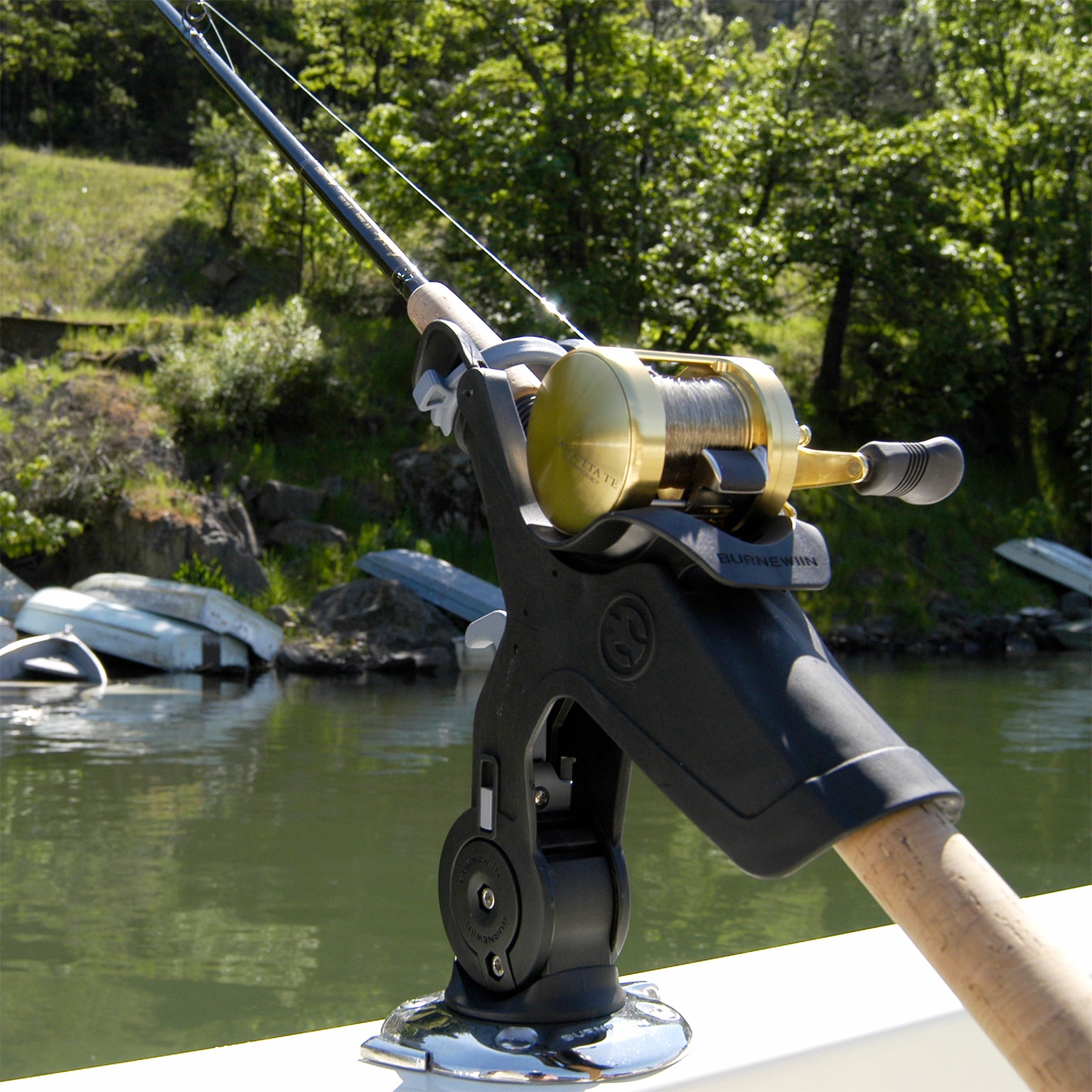 A closeup view of the Burnewiin RH5710 Rod Holder mounted on the gunwale of a boat with a lake shoreline in the background.