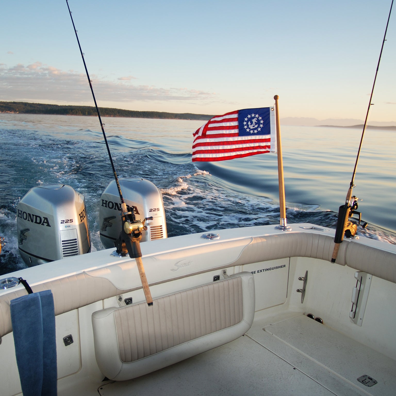 The Burnewiin FL6155 Flag Holder with a flag and next to other fishing rods, all positioned on the transom of a boat.