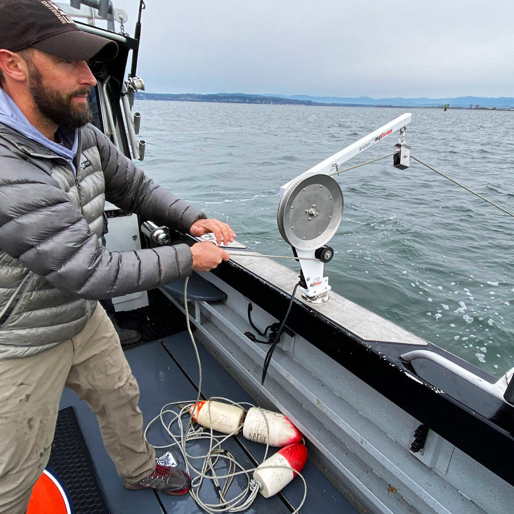 A fisherman altering the line of the PACPRO Pacific Pro Line Hauler that is inserted in the Burnewiin GM650 on the starboard gunwale. 