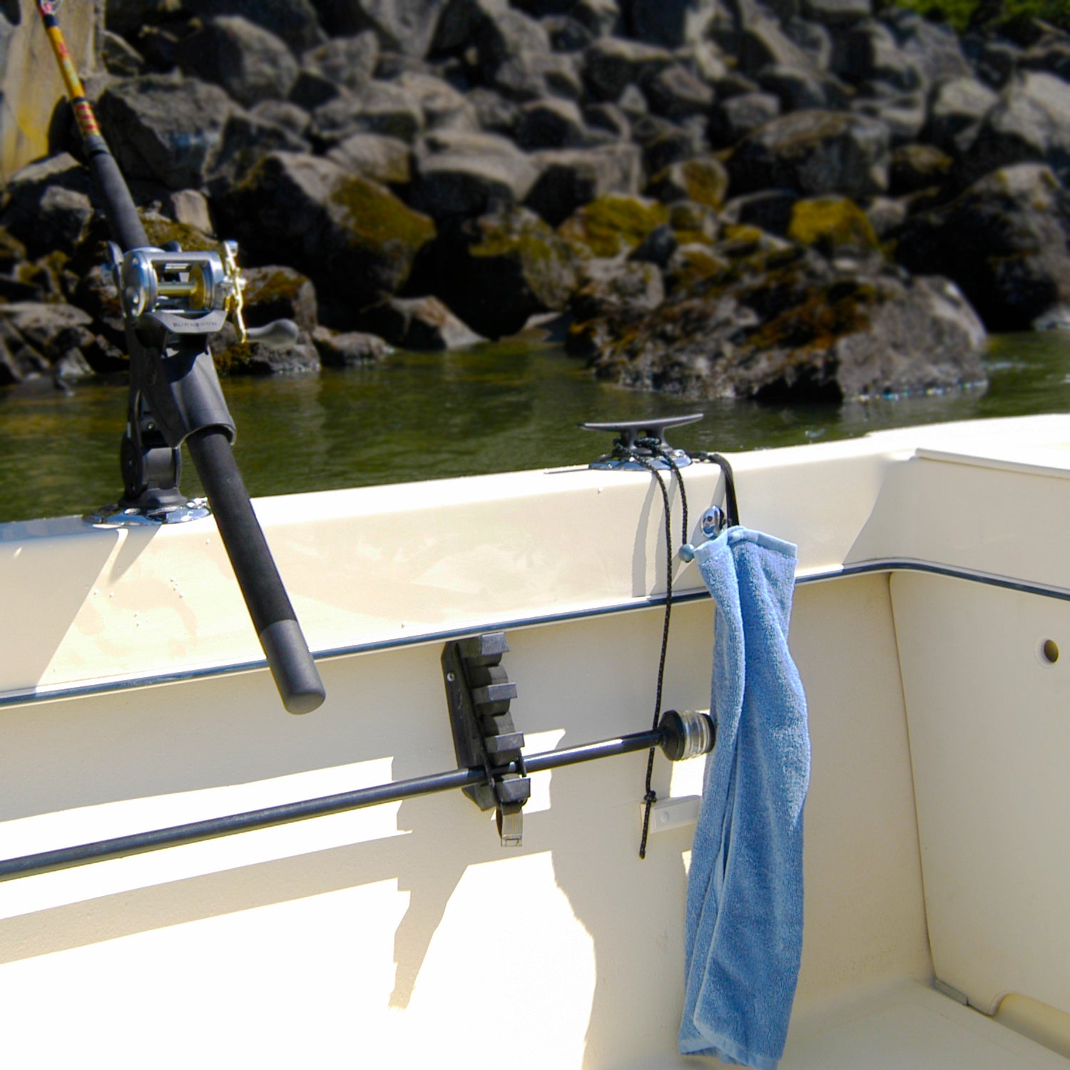 The Burnewiin TW1010 Burnewiin Towel next to an RH3740 Rod Holder clipped to a GM650 mount on the starboard gunwale of a fishing boat. 